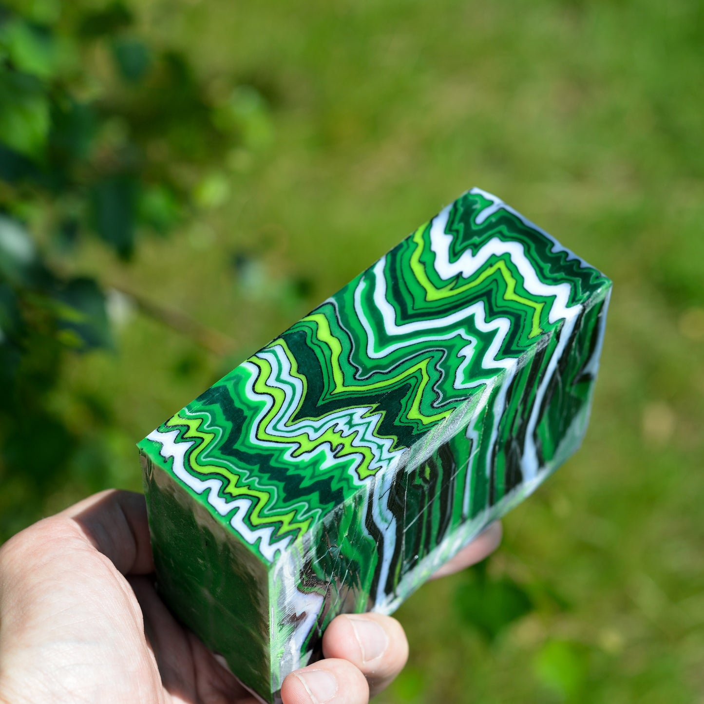 Detailed view of a high-contrast green composite material block showing deep wavy layers and vibrant neon green accents.