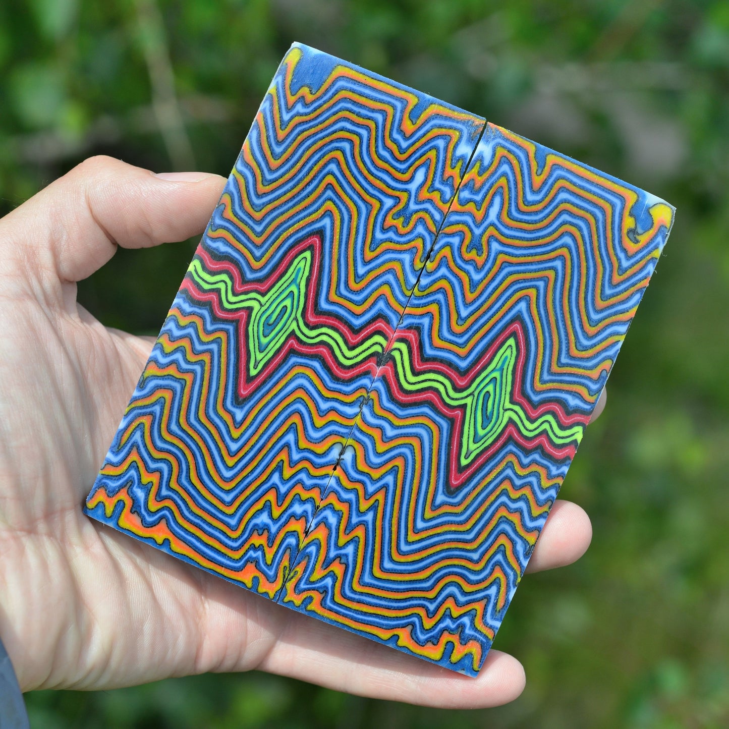 Handcrafted micarta handle material with symmetrical wavy layers in bright blue and orange for custom knife scales.