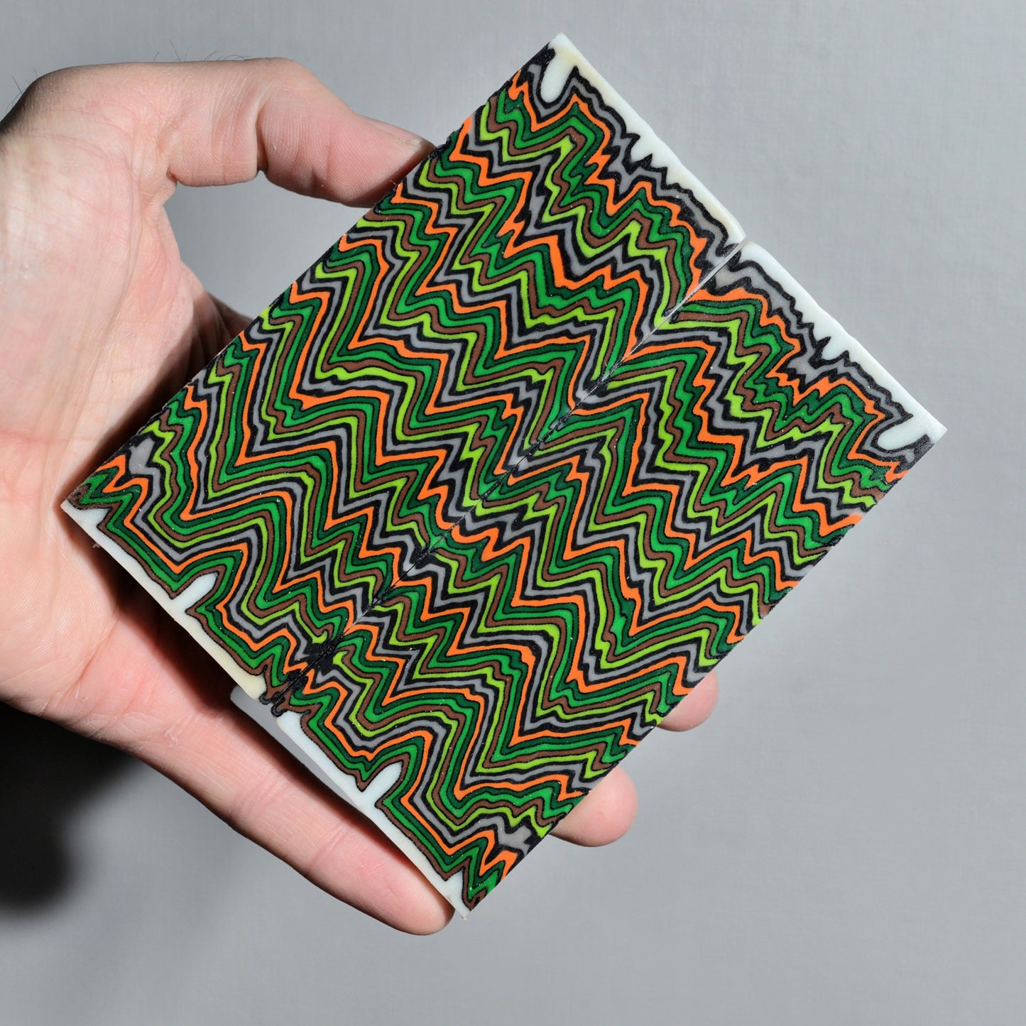 Handmade composite micarta block featuring green and orange zigzag layers