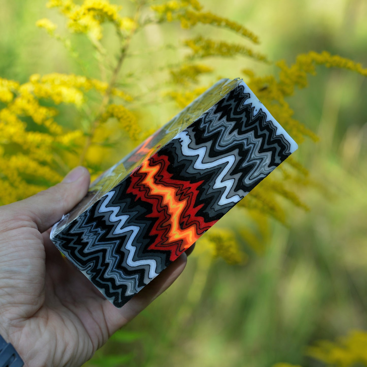 Red and black composite knife handle block with layered lava pattern held in hand #04