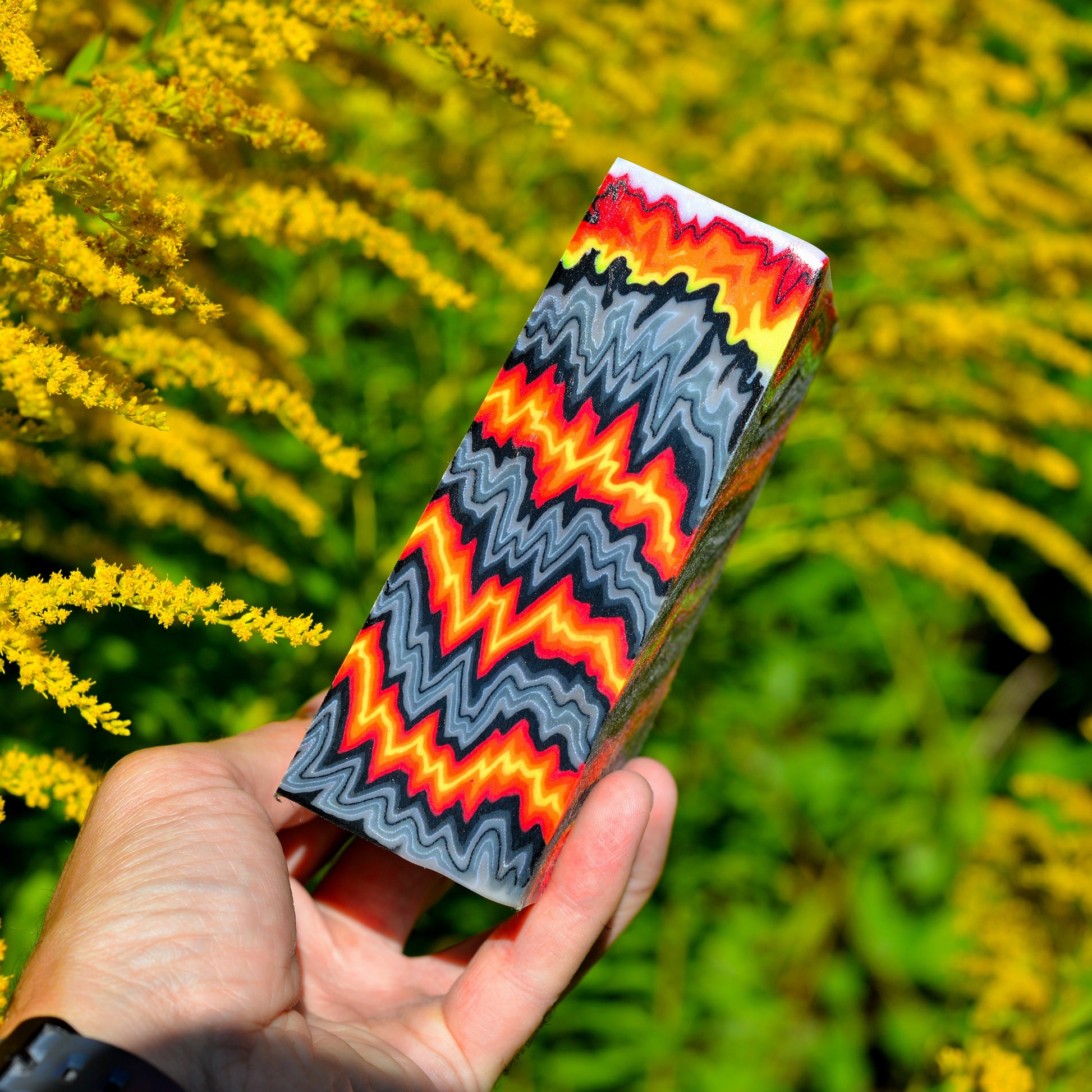 Red and yellow composite knife handle block with layered pattern held in hand #08