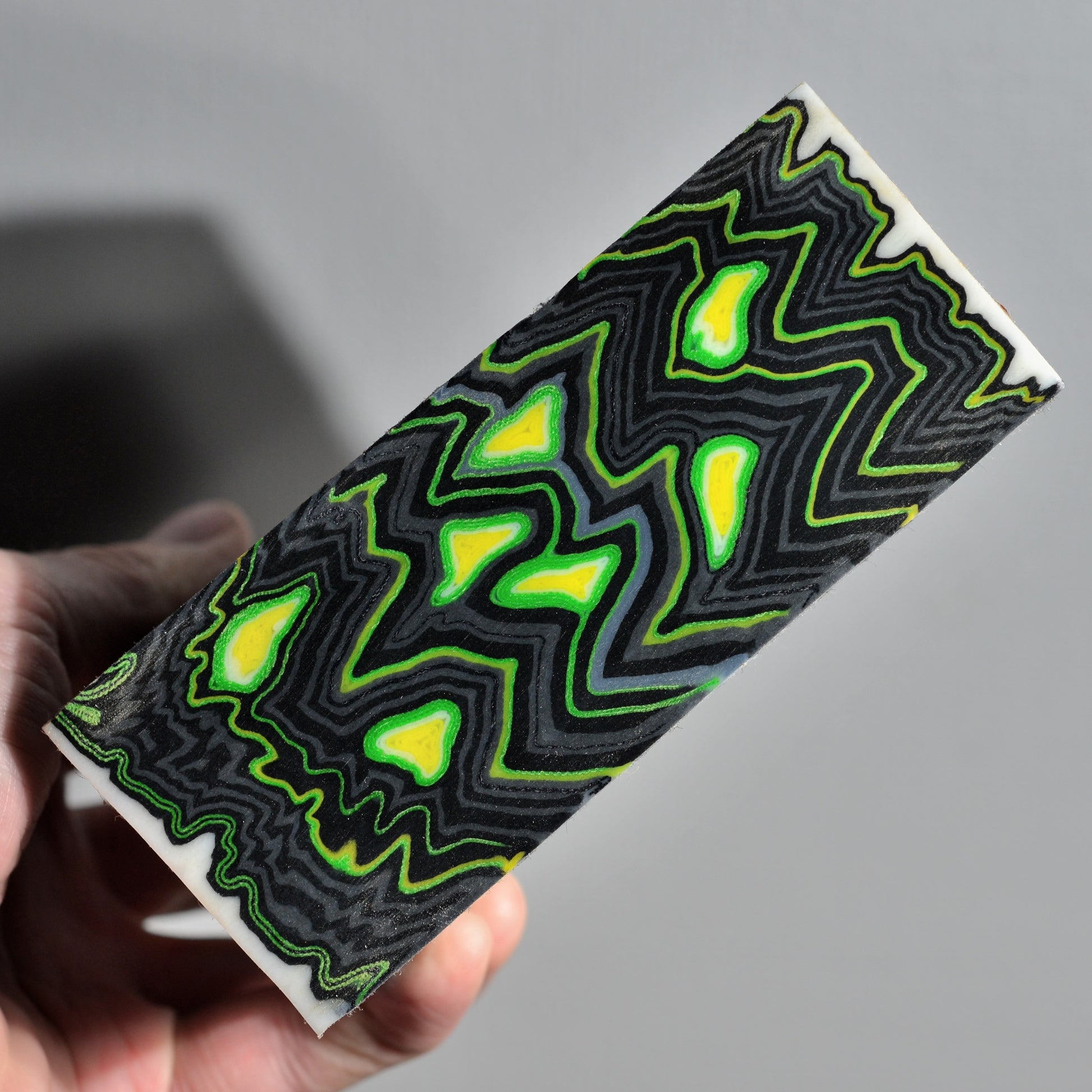 Pair of custom knife handle scales made from neon green and black micarta with bold abstract pattern, high-contrast composite material for custom knives