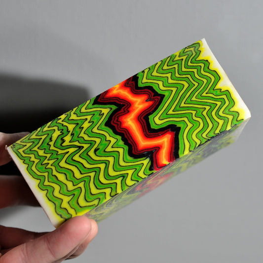 Pair of custom knife handle scales made from neon micarta with zigzag pattern in green, yellow, red and black, high-contrast composite material for custom knives