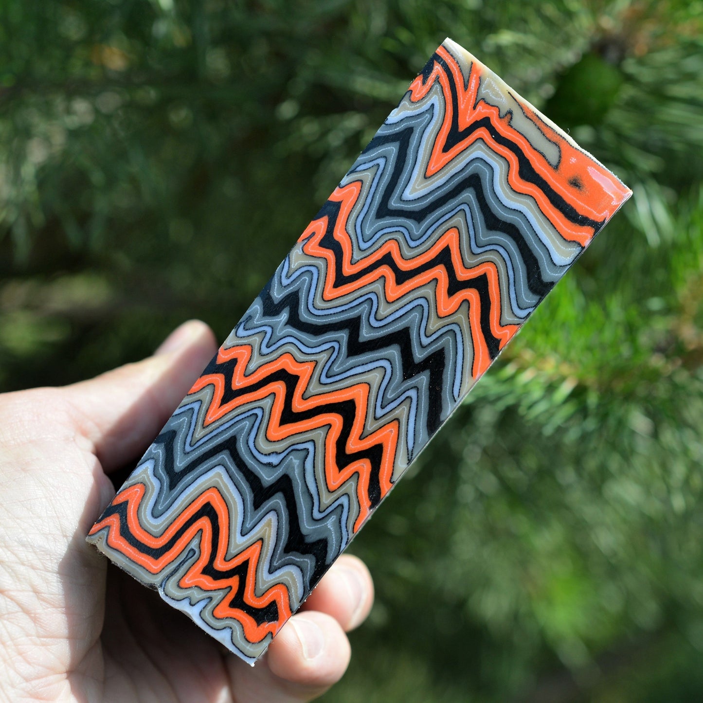 Custom micarta handle material blank featuring symmetrical wavy layers of orange and charcoal composite, ideal for heavy-duty EDC knife handles.