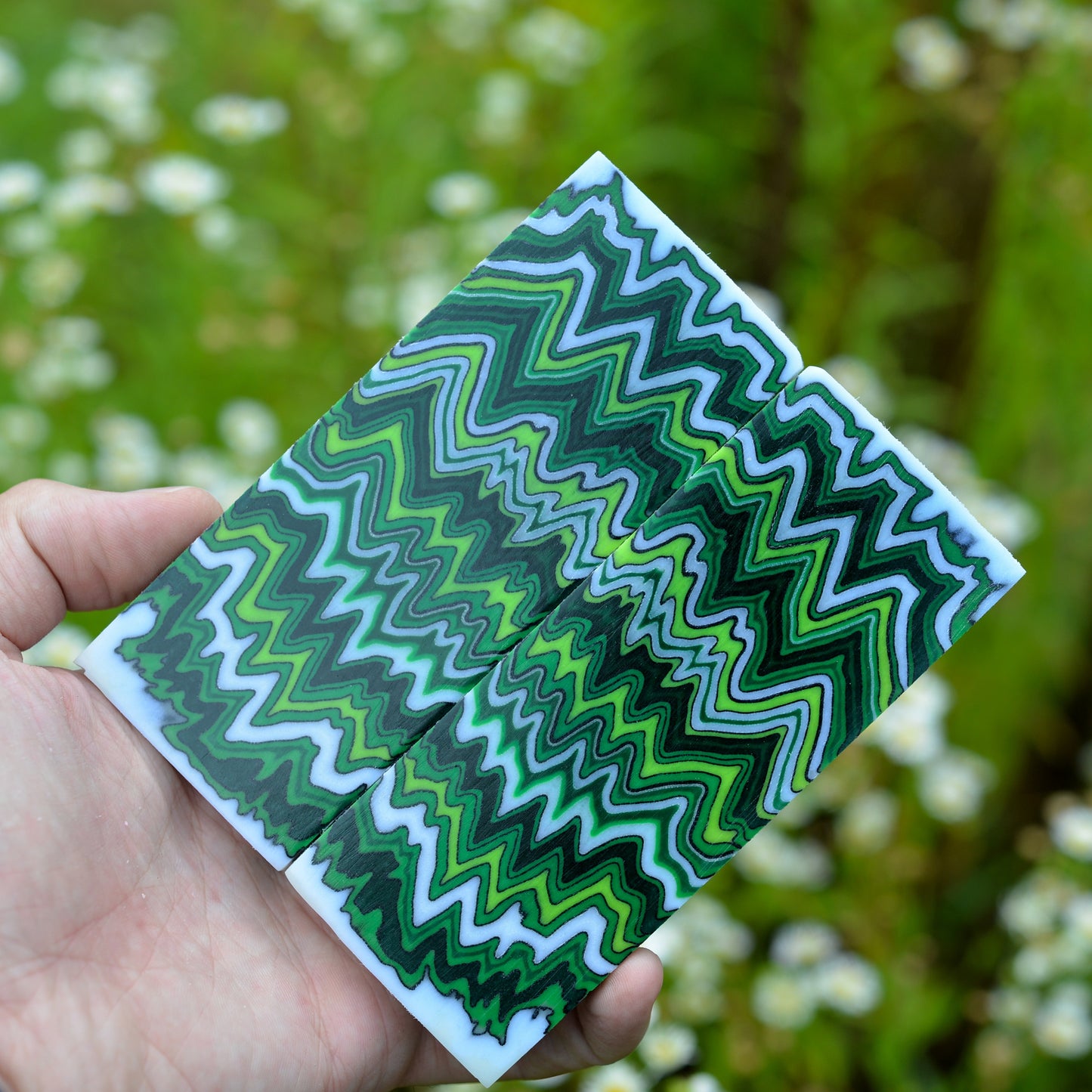 A pair of custom micarta knife scales featuring a symmetrical zigzag pattern in forest green, lime green, and dark charcoal grey.