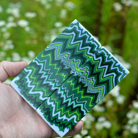 A pair of custom micarta knife scales featuring a symmetrical zigzag pattern in forest green, lime green, and dark charcoal grey.